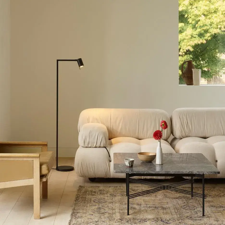 Brass floor lamp with cream shade creating a warm elegant glow beside a beige sofa.