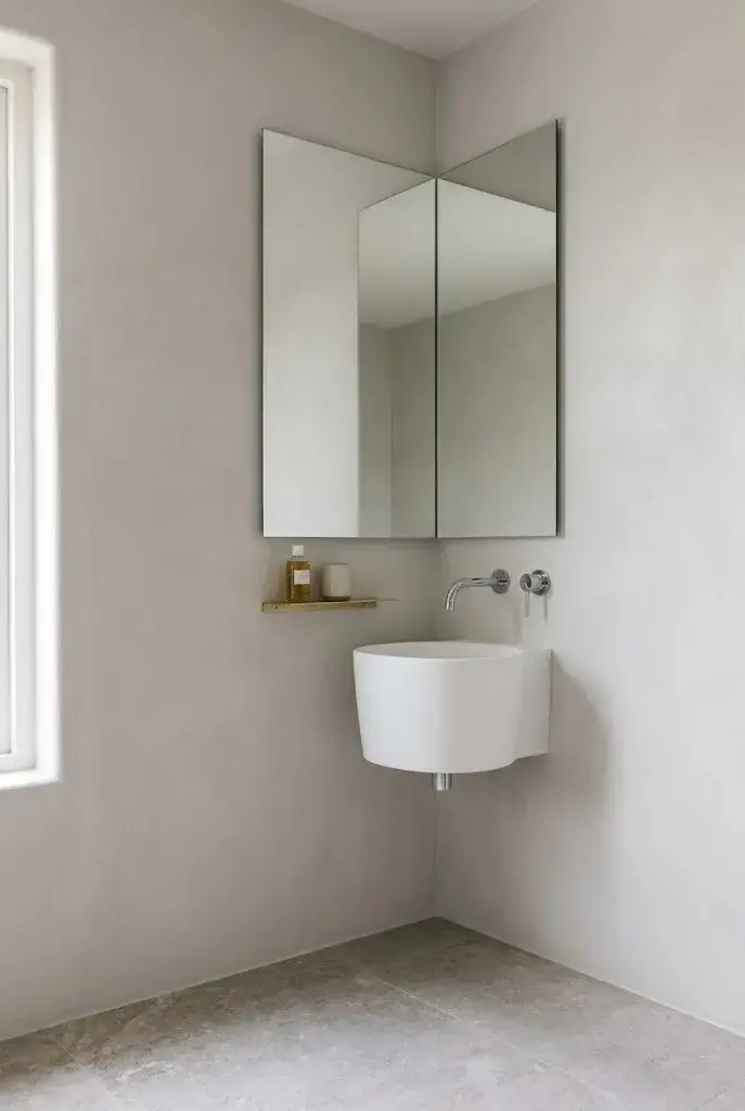 Compact white corner sink in a bright and space-saving small bathroom.