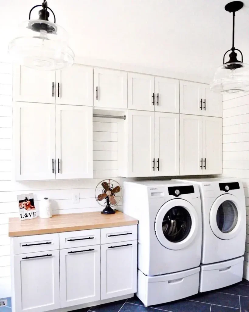 Farmhouse-inspired laundry room with white shaker cabinets, wood countertops, and rustic details