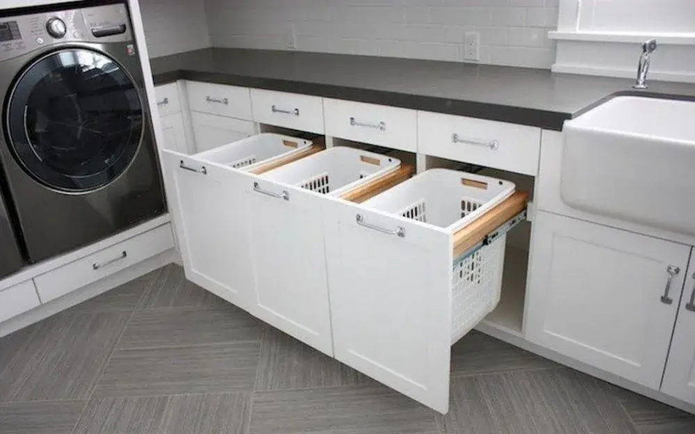 Laundry room with built-in cabinets, pull-out hampers, and organized laundry compartments.