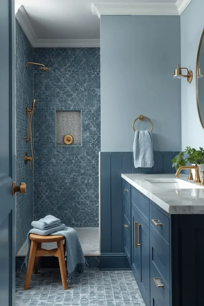 Layered blue bathroom combining pale blue walls, medium blue tiles, navy cabinetry, and white marble.