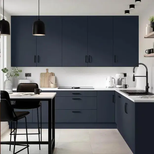 Navy blue kitchen cabinets paired with matte black handles, faucet, and pendant lights.