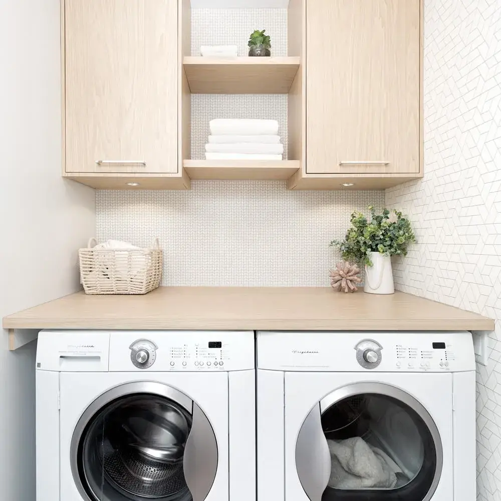 Small laundry room with a wooden folding countertop above white washing machines.