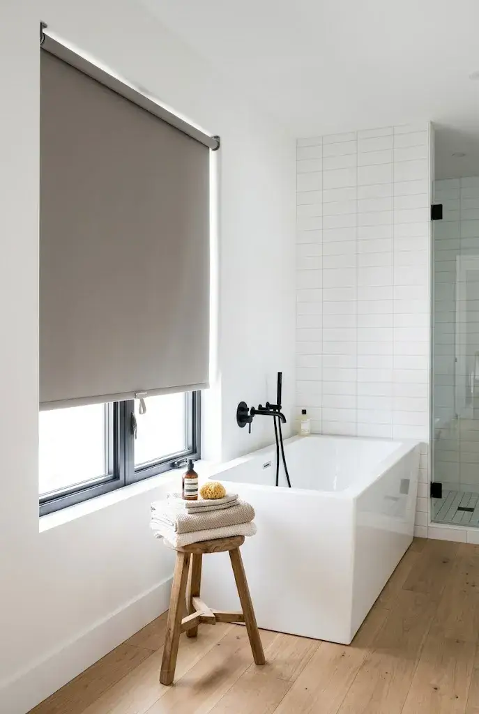 Waterproof roller shade providing practical privacy beside a bathroom bathtub